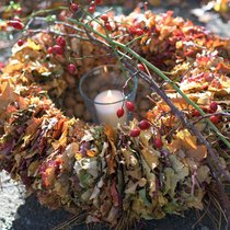 Der Kranz macht Ordnung im herbstlichen Laubhaufen. Eine Kerze in der Mitte lässt die filigranen Blätter leuchten.