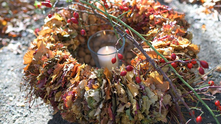 Der Kranz macht Ordnung im herbstlichen Laubhaufen. Eine Kerze in der Mitte lässt die filigranen Blätter leuchten.